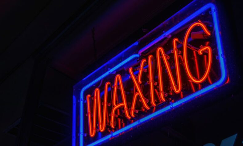 Vibrant neon waxing sign glowing in blue and orange against a dark background. - Photo by Robert So on Pexels