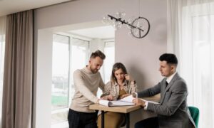 A couple consults with a real estate agent in a modern indoor setting, reviewing property documents. - Photo by Alena Darmel on Pexels